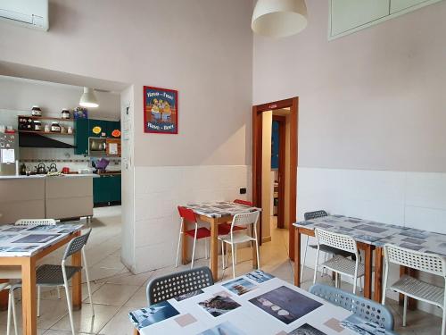 ein Zimmer mit Tischen und Stühlen sowie einer Küche in der Unterkunft Hostel Mancini Naples in Neapel