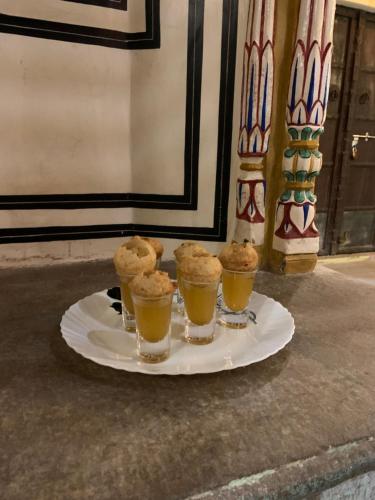 a plate with four cups of drinks on a table at Jaipur Haveli in Jaipur