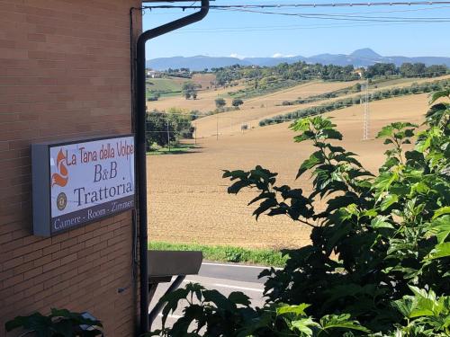 a sign on the side of a brick building looking at a field with a big at La Tana della Volpe B.&.B. in Montecassiano