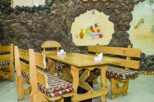 a wooden table and chairs with a stone wall at Zangezur Hotel in Goris