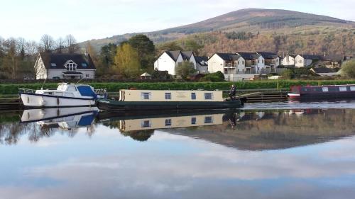 a couple of boats docked in a river with houses at Mount Brandon Cottages Graiguenamanagh in Graiguenamanagh