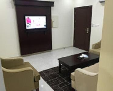 a living room with a table and chairs and a tv at Aseel for serviced Apartments اسيل للشقق المخدومة in Jeddah