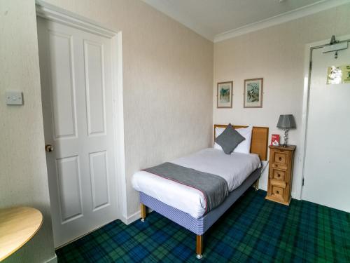 a small bedroom with a bed and a table at The National Hotel in Dingwall