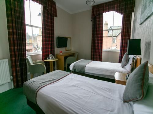 a hotel room with two beds and two windows at The National Hotel in Dingwall