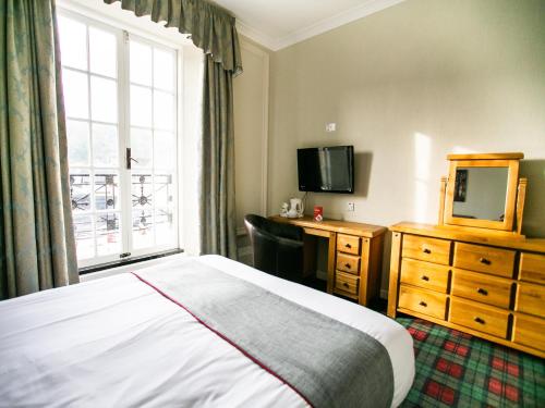 a hotel room with a bed and a dresser and a window at The National Hotel in Dingwall