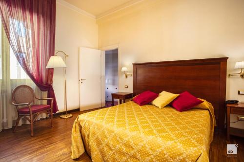 a hotel room with a bed with yellow and red pillows at Hotel Alessandro Della Spina in Pisa
