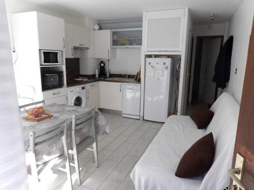 uma cozinha com uma mesa e um frigorífico branco em Hameau des Thermes - appartement rez de chaussée em Saint-Lary-Soulan