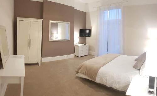 a bedroom with a bed and a dresser and a mirror at Cottage Grove Homestay rooms in Portsmouth