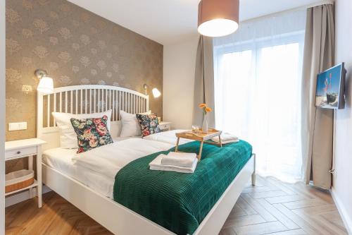 a bedroom with a white bed with a green blanket at Kapitänshaus Sellin mit Sauna und Kamin in Ostseebad Sellin