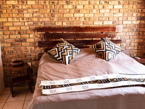 a bed with two pillows and a brick wall at Injabulo in Marloth Park