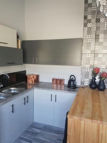 a kitchen with white cabinets and a wooden table at ikibiki in Beaufort West