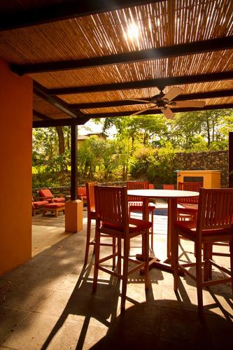 a patio with a table and chairs under a wooden roof at Jet Luxury at Langosta Beach Resort & Villas in Tamarindo