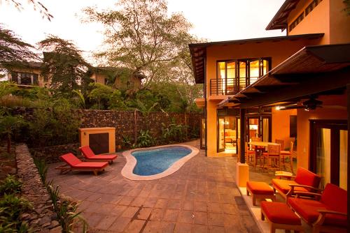 a patio with chairs and a swimming pool next to a house at Jet Luxury at Langosta Beach Resort & Villas in Tamarindo