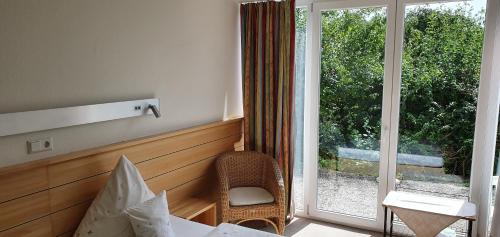 um quarto com uma cama e uma janela com uma cadeira em Landgasthof/Hotel Hirsch im Grünen em Mehrstetten