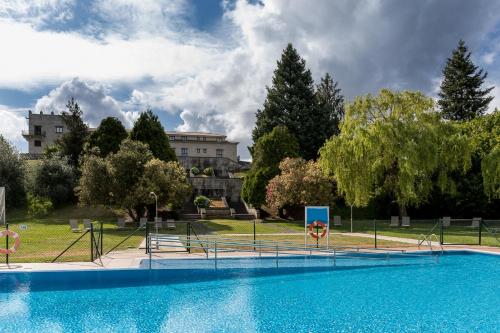 a large blue swimming pool with a building in the background at Parador de Tui in Tui