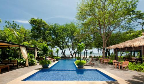 a pool at a resort with tables and chairs at Jet Luxury at Langosta Beach Resort & Villas in Tamarindo