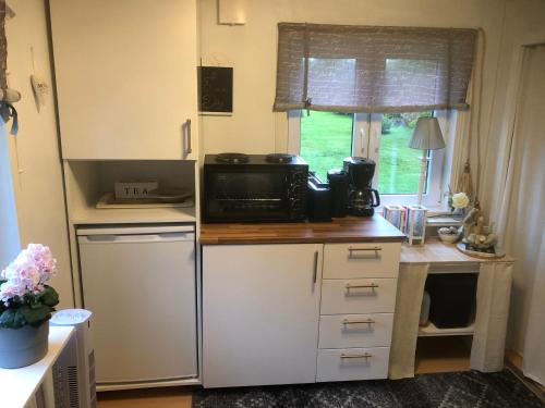 eine kleine Küche mit einer Mikrowelle und einem Kühlschrank in der Unterkunft Villa Lillgården with Sauna and Jacuzzi in Norrköping