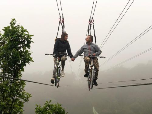 two people riding bikes on a zip line at Glamping y Chalet Aventura Park Villa De Leyva La Periquera in Villa de Leyva