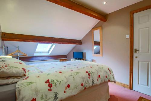 a bedroom with a bed with a floral bedspread at Foxhill Fold in Gisburn