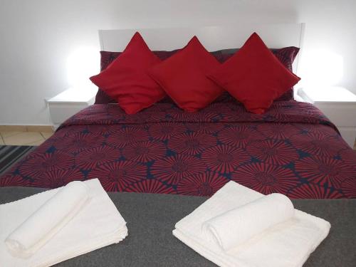 a bed with red pillows and white towels on it at Hillary E Vale Room in Rome