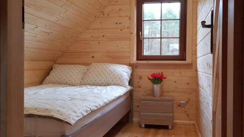 Bett in einem Holzzimmer mit Fenster in der Unterkunft DOMEK AGA in Kruklanki