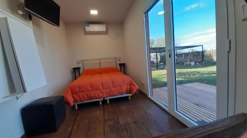Schlafzimmer mit einem Bett und einer großen Glasschiebetür in der Unterkunft LEKU Lodge & Deptos in General Acha