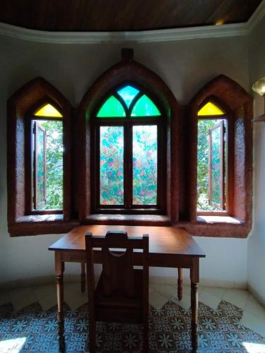 a table with a chair in front of two windows at Porsu in Canacona
