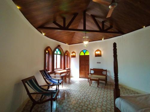 a living room with chairs and a wooden ceiling at Porsu in Canacona