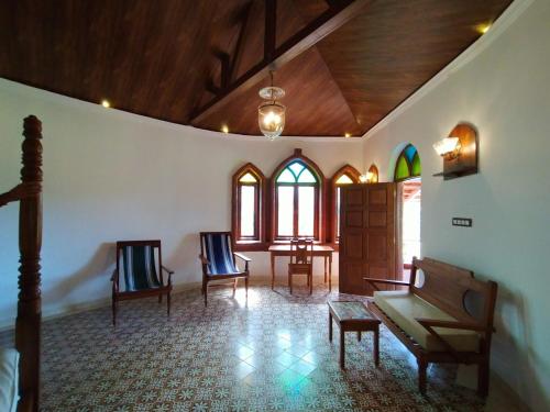 a living room with chairs and a table and windows at Porsu in Canacona