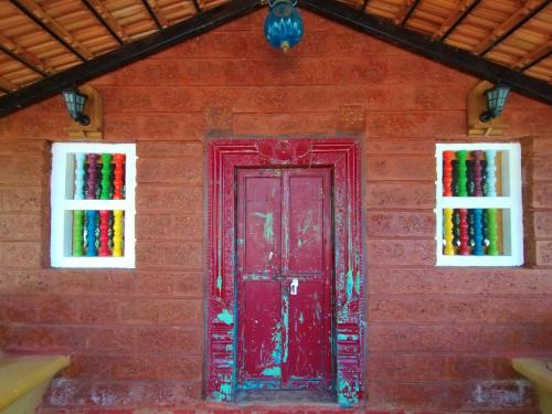 a red door in a red brick wall with two windows at Porsu in Canacona