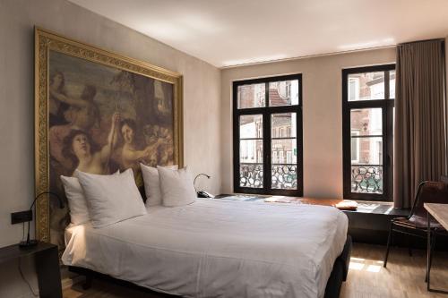 a bedroom with a large bed with a painting on the wall at HotelO Kathedral in Antwerp