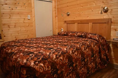 a bedroom with a large bed in a wooden room at Tall Chief Camping Resort Cottage 1 in Pleasant Hill