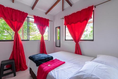 a bedroom with red curtains and a bed with a chair at CAMPO VALDES PARK HOSTEL in Medellín