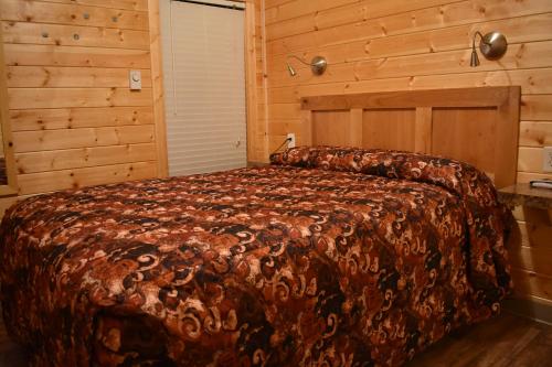 une chambre avec un grand lit dans une pièce en bois dans l'établissement Tall Chief Camping Resort Cottage 4, à Pleasant Hill