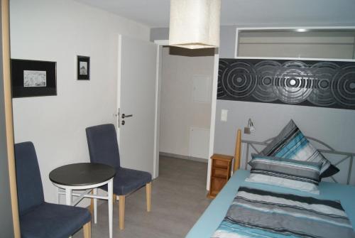 a bedroom with a bed and two chairs and a table at Ferienwohnung Im Alftal, Bleialf in Bleialf
