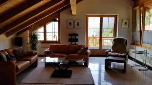 a living room with couches and a table and windows at Privathaus Achensee in Achenkirch