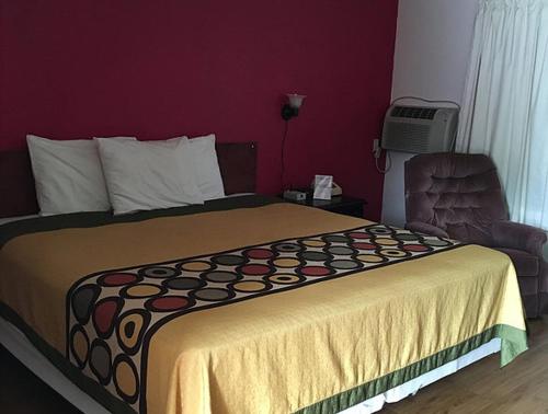 a hotel room with a bed and a chair at Tarragon Motel in Marinette