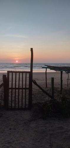a sunset on a beach with a fence and the ocean at OmBodhi Retreat in Kumta