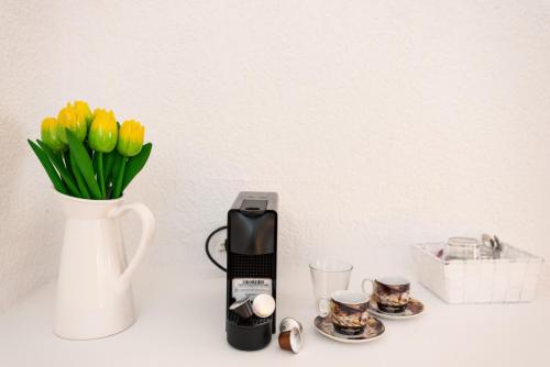 a vase of yellow tulips next to a coffee maker and cups at Blue Mountain Guesthouse by Seablue in Arachova