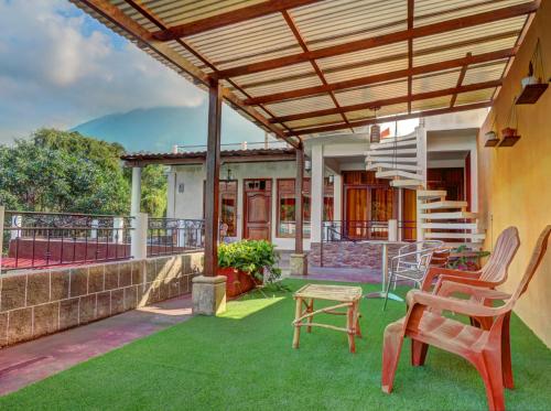 d'une terrasse avec des chaises et une table sur la pelouse. dans l'établissement SHANTI SHANTI Hotel & Restaurante, à San Pedro de la Laguna