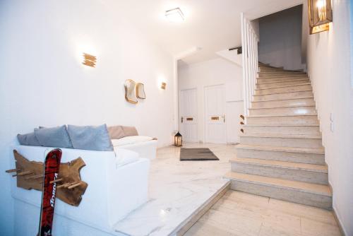 a white living room with stairs and a guitar at Blue Mountain Guesthouse by Seablue in Arachova