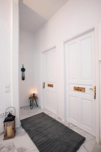 a hallway with white walls and white doors and a rug at Blue Mountain Guesthouse by Seablue in Arachova