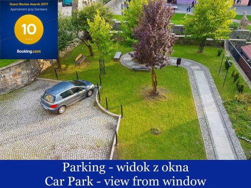 een auto geparkeerd in een park naast een boom bij Apartament Przy Starówce - Stella in Bolesławiec