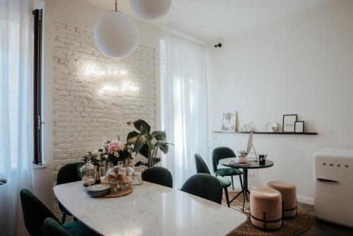 a dining room with a white table and green chairs at Cà Bèla - Porta Romana in Milan