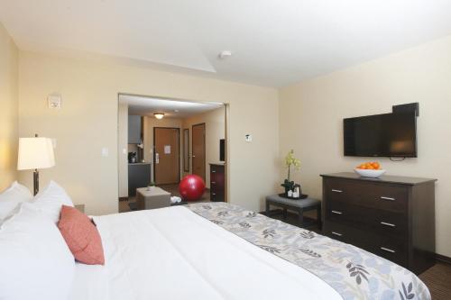 a bedroom with a white bed and a flat screen tv at Pomeroy Inn & Suites at Olds College in Olds