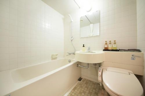 a bathroom with a toilet and a sink and a tub at Oarai Park Hotel in Oarai
