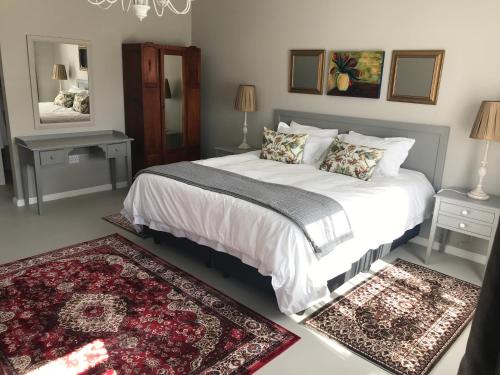 a bedroom with a large white bed with two rugs at Steenkoppies Estate semi self catering unit 2 in Magaliesburg