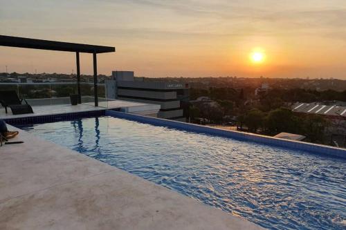 a swimming pool on top of a building with the sunset at Departamento 1 habitación zona exclusiva in Asuncion