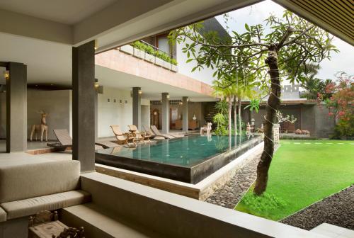 a patio area with a pool and a tree at Alindra Villa in Nusa Dua