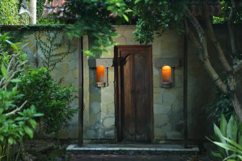 a wooden door with two lights on a stone wall at Alindra Villas & Spa in Nusa Dua